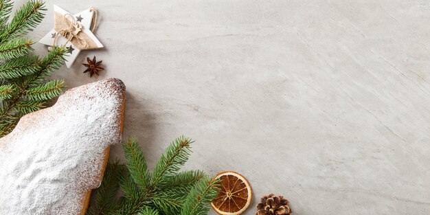 Zelfgemaakt gebak, koekjes in de vorm van een kerstboom, vuren takken en decoraties op een stenen tafel. Bovenaanzicht.