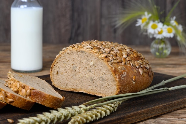 Zelfgemaakt gesneden brood op donkere snijplank en melk op houten tafel