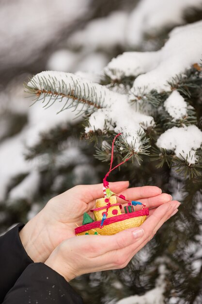 Zelfgemaakt kerstspeelgoed in de handen van het meisje op de achtergrond van de kerstboom