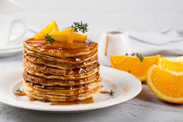 Zelfgemaakt ontbijt of brunch: pannenkoeken in Amerikaanse stijl geserveerd met sinaasappel en besprenkelde karamelsiroop