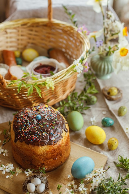 Zelfgemaakt paasbrood natuurlijk geverfd paaseieren ham bieten boter in mand op rustieke tafel met lentebloesems en linnen servet Bovenaanzicht Traditioneel paasvoedsel