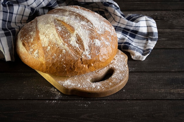 Zelfgemaakt rustiek brood gesneden met een servet op donkere houten plaat met kopieerruimte