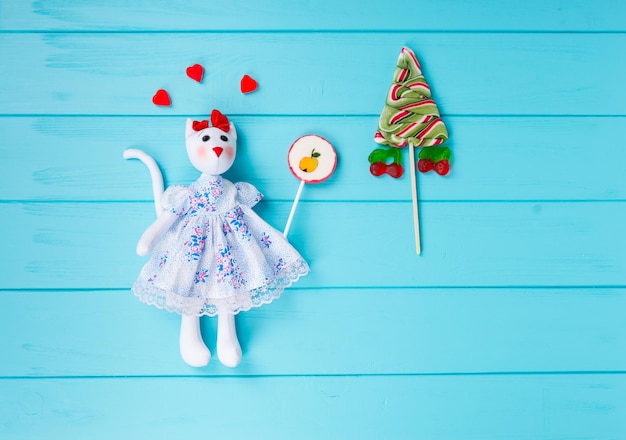 Zelfgemaakt speelgoed in de vorm van een kat met gummy harten rond het vasthouden van snoep in de buurt van lolly als een kerstboom op houten turquoise bord