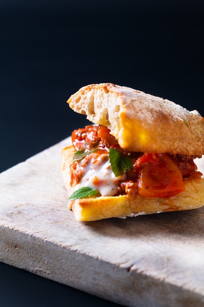 Zelfgemaakt voedselconcept Organische bolognese sandwich van het grill artisanale brood op zwarte