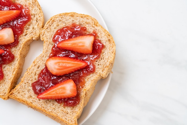 zelfgemaakt volkorenbrood met aardbeienjam en verse aardbeien