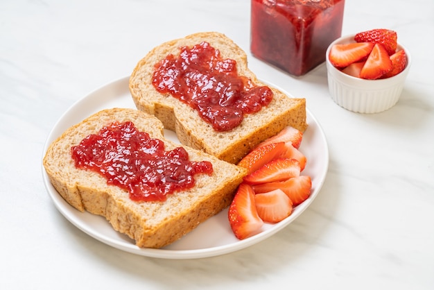 Zelfgemaakt volkorenbrood met aardbeienjam en verse aardbeien