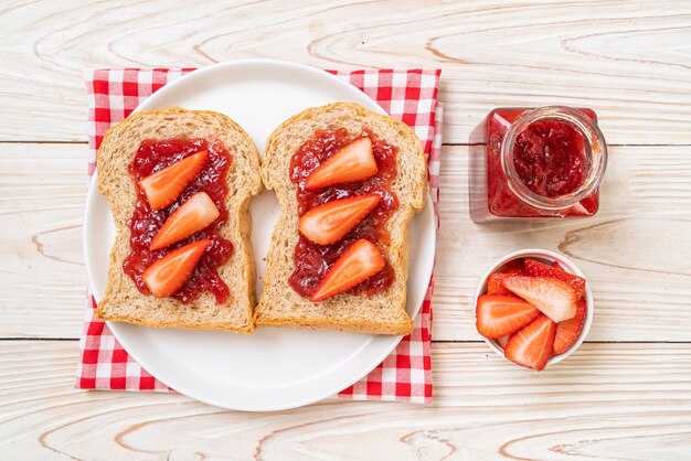 Zelfgemaakt volkorenbrood met aardbeienjam en verse aardbeien