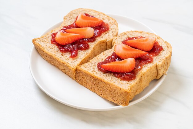 zelfgemaakt volkorenbrood met aardbeienjam en verse aardbeien