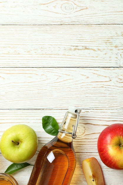 Zelfgemaakte appelazijn en ingrediënten op witte houten tafel