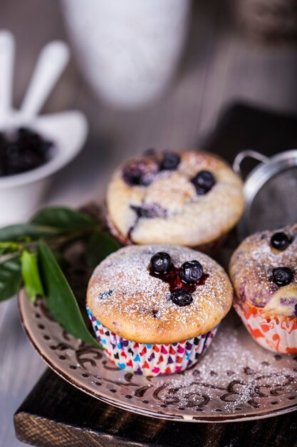 Zelfgemaakte bosbessenmuffins met poedersuiker op houten achtergrond