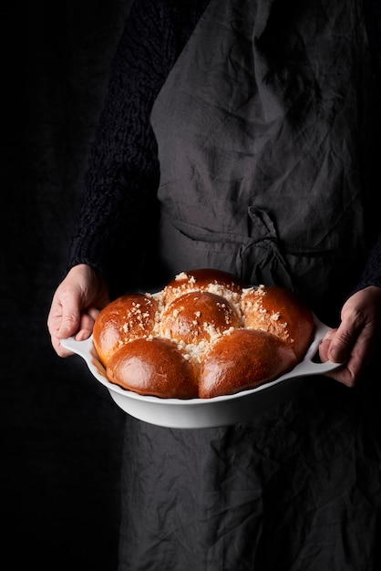 Zelfgemaakte brioche in witte lade gehouden door de hand van een vrouw