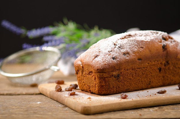 Zelfgemaakte cake met rozijnen en poedersuiker op houten tafel.