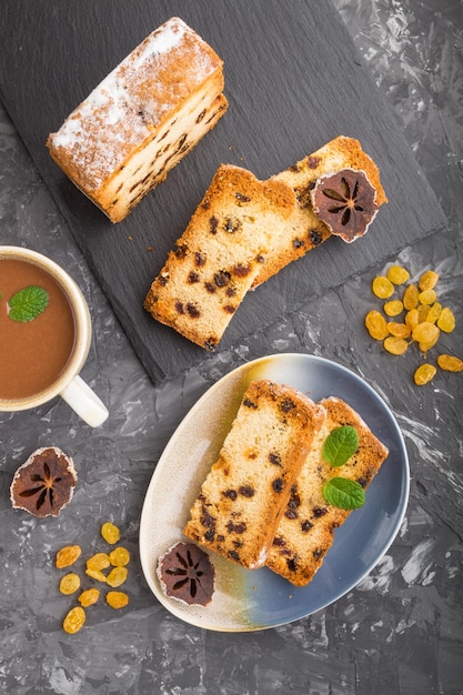 Zelfgemaakte cake met rozijnen, gedroogde persimmon en een kop warme chocolademelk op een zwarte betonnen ondergrond. bovenaanzicht, plat lag, kopieer ruimte.