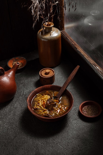 Zelfgemaakte champignonsoep op een tafel bij een raam in een rustiek oud huis. Nationale tradities, grootmoeders recept voor gezond eten. Donker humeurig