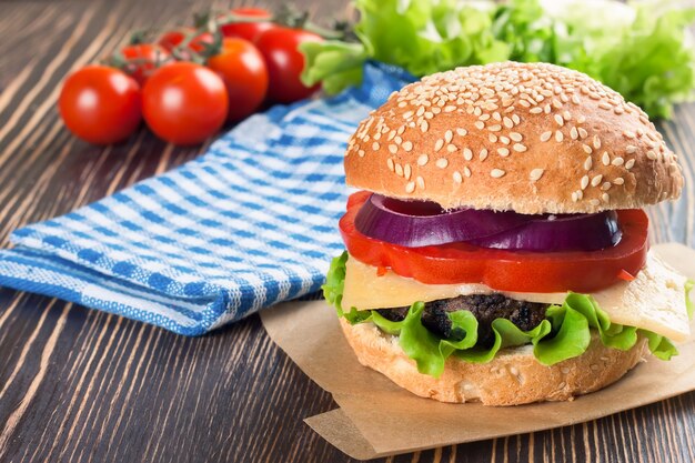 Zelfgemaakte cheeseburger met runderpasteitjes en verse salade op seasame-broodjes, gesered op bruine houten tafel.