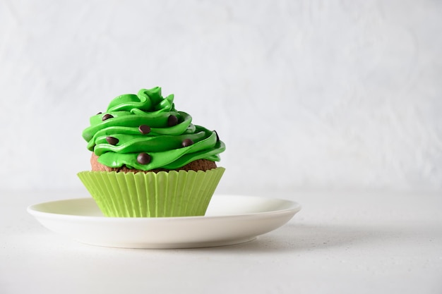 Zelfgemaakte chocolade cupcake met groene slagroom en hagelslag op witte achtergrond Close-up verjaardagsviering