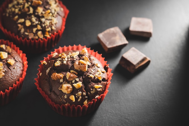 Zelfgemaakte chocolade muffins of cupcakes besprenkeld met noten op donkere achtergrond