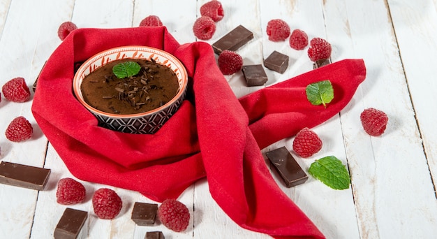 Zelfgemaakte chocolademousse met framboos op witte houten oppervlak