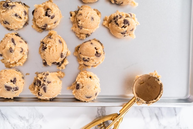 Zelfgemaakte chocoladeschilferkoekjes deeg scoops op een bakplaat.