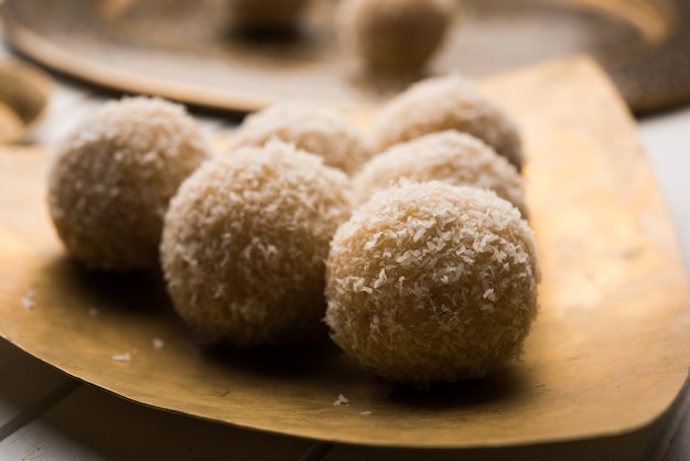 Foto zelfgemaakte coconut sweet laddoo of nariyal laddu gemaakt met gecondenseerde melk en suiker, populair festivalvoedsel. geserveerd op een humeurige achtergrond, selectieve focus