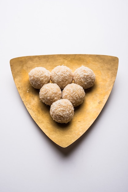 Foto zelfgemaakte coconut sweet laddoo of nariyal laddu gemaakt met gecondenseerde melk en suiker, populair festivalvoedsel. geserveerd op een humeurige achtergrond, selectieve focus