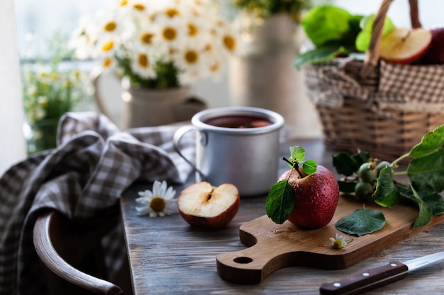 Zelfgemaakte compote van zomerappels op een houten tafel bij het raam met wilde kamille in de pot