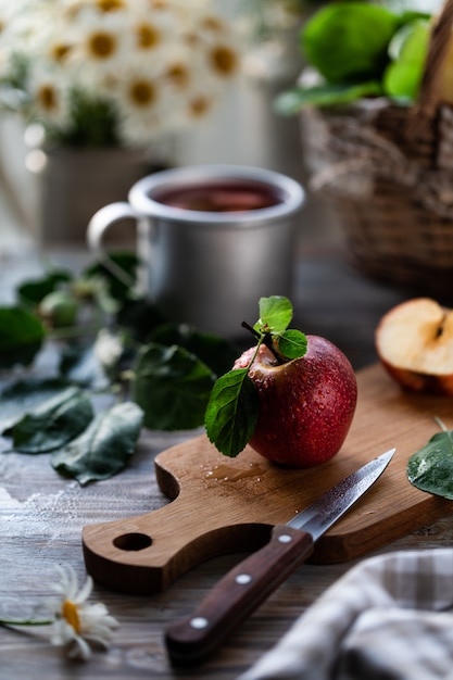 Zelfgemaakte compote van zomerappels op een houten tafel bij het raam met wilde kamille in de pot