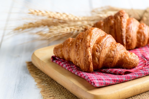 Zelfgemaakte croissant op houten plaat en witte houten bakkerij als achtergrond