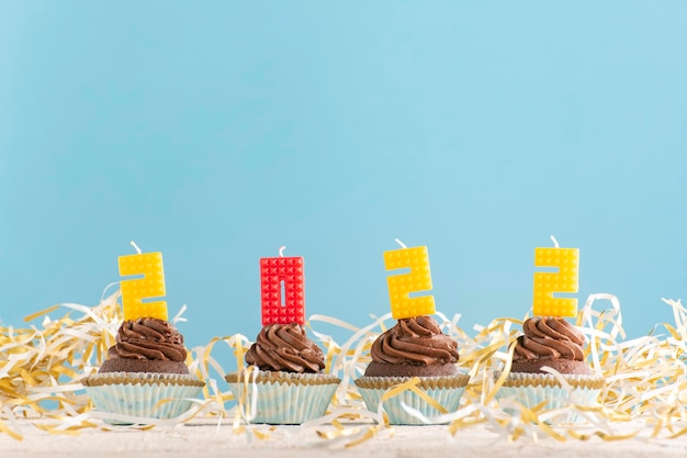 Zelfgemaakte cupcakes en kaarsen-nummers 2022 op blauwe achtergrond. Ruimte kopiëren.