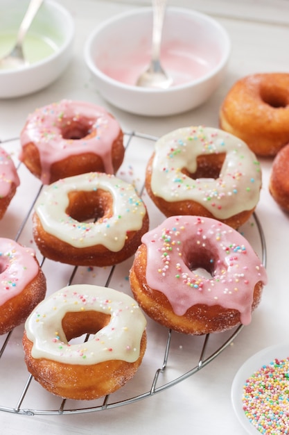 Zelfgemaakte donuts versierd met gekleurde suikerglazuur en gekleurde suiker op een lichte achtergrond.