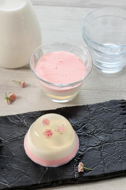 Zelfgemaakte doorzichtige mini-roos roze gelaagde pudding in een kopje, een variant van eetbare bloempuddingdecoratie