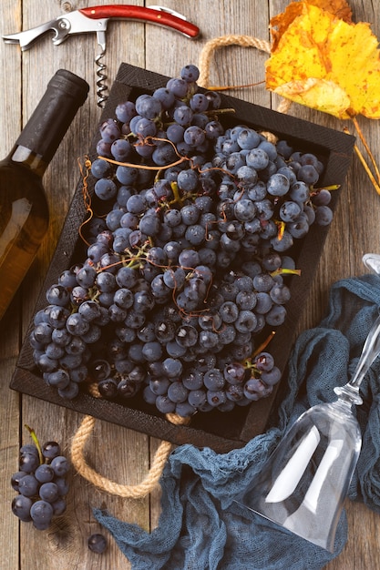 Zelfgemaakte druiven in een zwarte doos, een fles wijn en kurkentrekker op oude houten achtergrond. Vintage-stijl. Getinte afbeelding. Bovenaanzicht