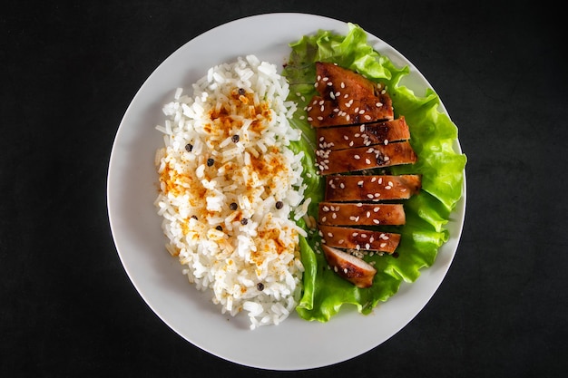 Zelfgemaakte eten teriyaki kip met witte rijst en peper op een zwarte achtergrond