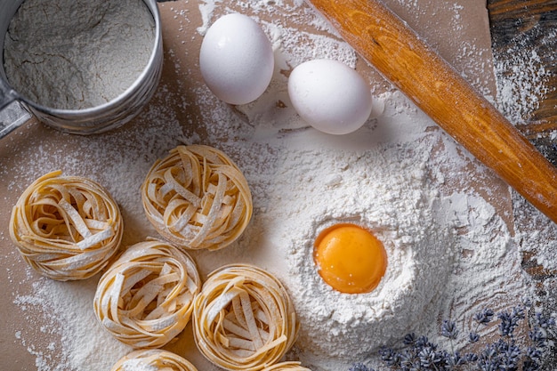 Zelfgemaakte fettuccine pasta gevouwen in de vorm van een nest Thuis koken met ingrediënten voor zelfgemaakte traditionele Italiaanse fettuccine pasta