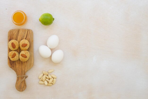 Zelfgemaakte fitnesskoekjes met amandelpasta, sesamzaadjes, honing en zonder bloem op een houten snijplank. Vrije ruimte voor een tekst.