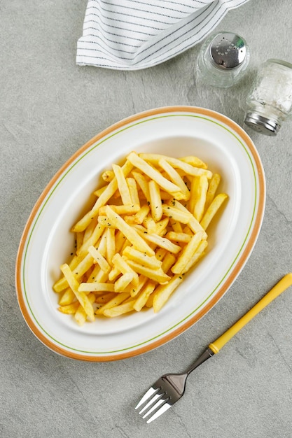 Zelfgemaakte frietjes in een ovale keramische kom op een cementtafel als achtergrond Bovenaanzicht