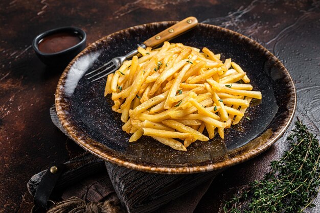 Zelfgemaakte gebakken aardappel frietjes in rustieke palte met tijm. Donkere achtergrond. Bovenaanzicht.