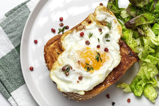 Zelfgemaakte gebakken eieren met brioche en sla salade op witte plaat