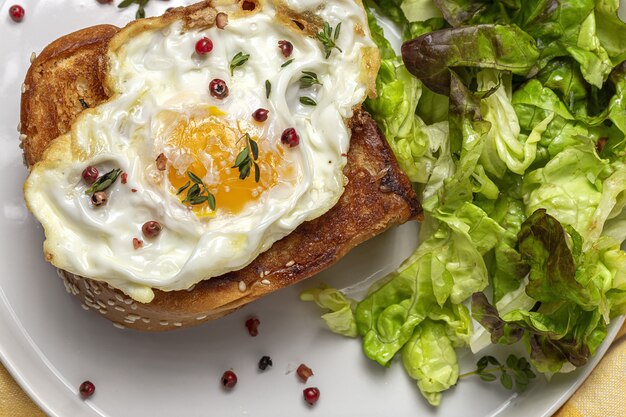 Zelfgemaakte gebakken eieren met brioche en sla salade op witte plaat