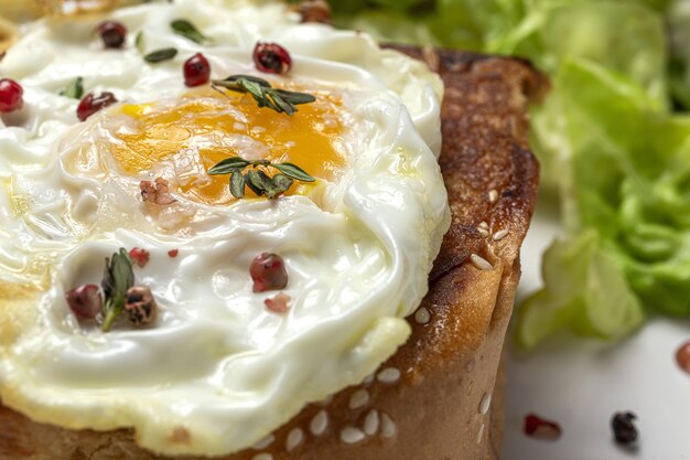 Zelfgemaakte gebakken eieren met brioche en sla salade op witte plaat