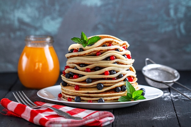 Zelfgemaakte gebakken pannenkoeken met verse bessen en honingpot voor een heerlijk ontbijt