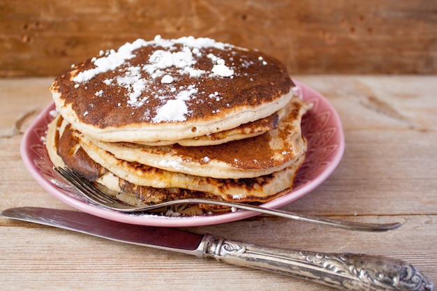 Zelfgemaakte gebakken pannenkoeken op een zwarte gietijzeren koekenpan met bessen, frambozen, veenbessen en bramen