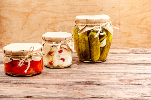 Zelfgemaakte gefermenteerde producten in glazen potten - zuurkool, gepekelde tomaten, augurken, houten oppervlak