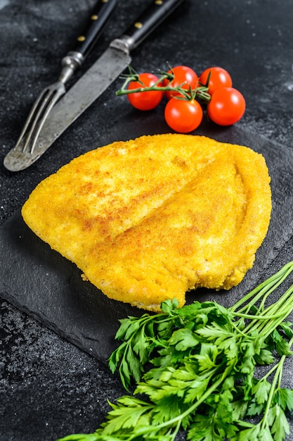 Zelfgemaakte gepaneerde duitse weiner schnitzel. zwarte achtergrond. bovenaanzicht.