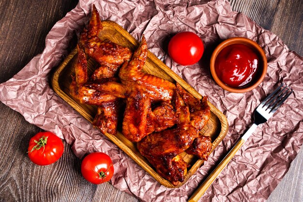 Zelfgemaakte gerechten gegrilde kippenvleugels met saus en tomaten