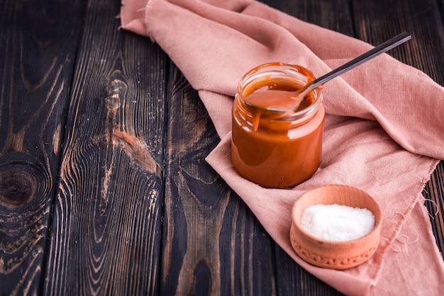 Zelfgemaakte gezouten karamel op een donkere tafel met een mooie zwarte lepel en melk.