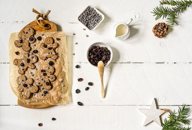 Zelfgemaakte gingerbread man koekjes met droge veenbessen, druppels chocolade en ijssuikerglazuur.