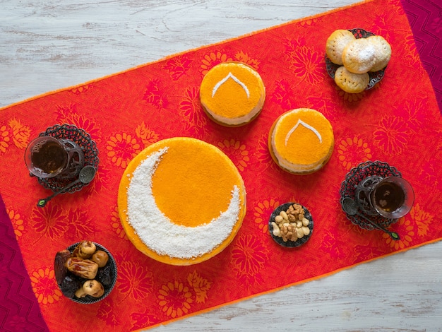 Zelfgemaakte gouden cake met een halve maan, geserveerd met theekop en dadels. ramadan muur