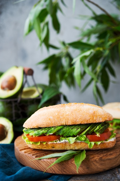 Zelfgemaakte groente sandwich met roomkaas, verse avocado en tomaten op een houten tafel. Verticale foto. Selectieve aandacht.