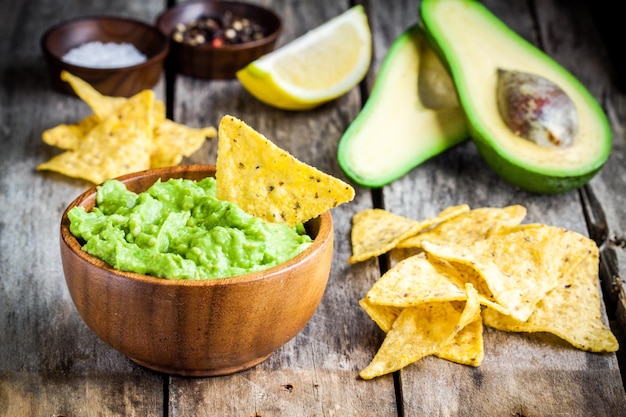 Zelfgemaakte guacamole met maïschips op rustieke houten tafel